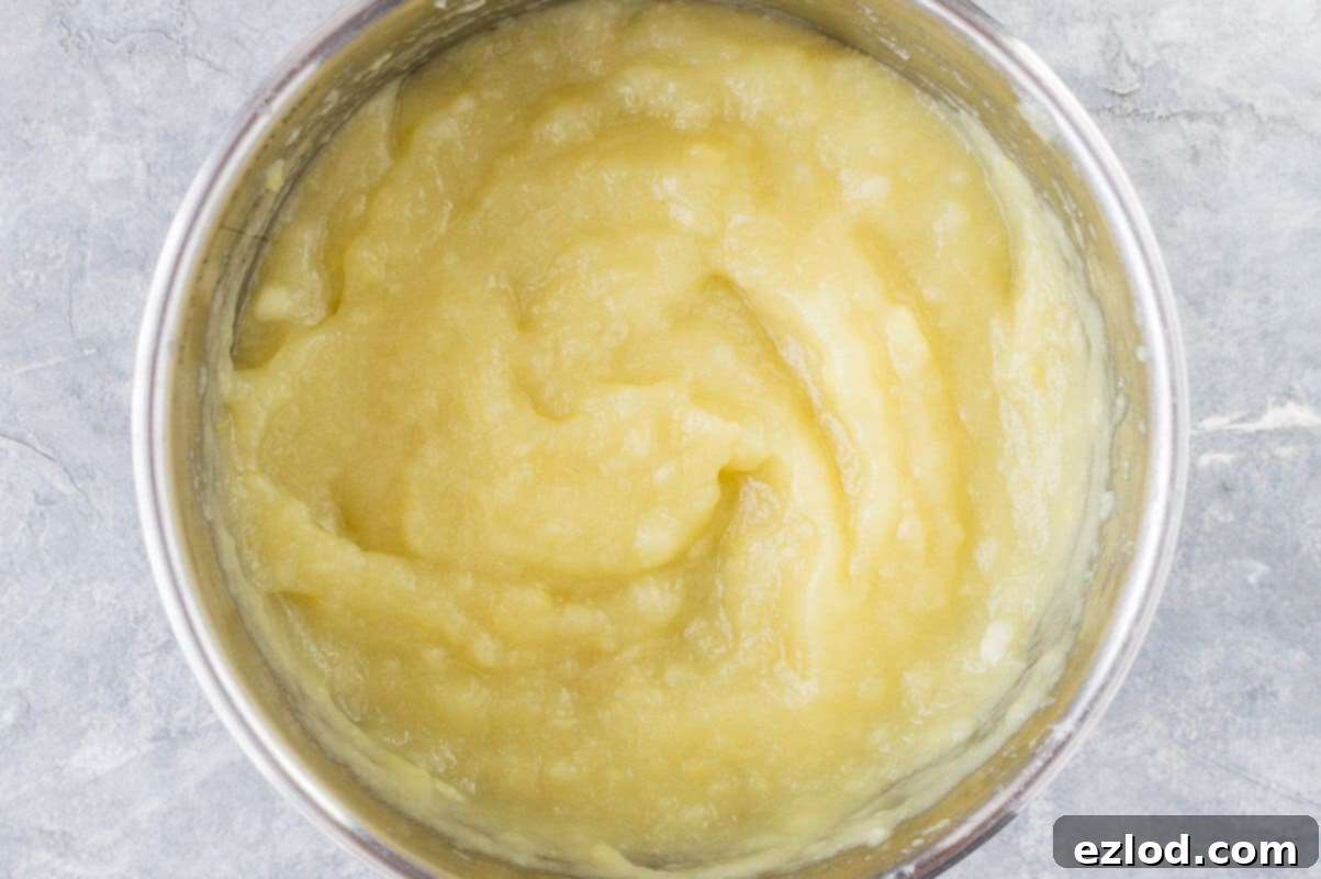 A bowl of freshly made, chunky homemade unsweetened applesauce, showcasing its natural texture and warm color.