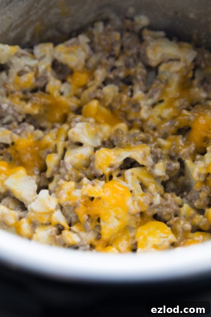 A close-up shot of the Instant Pot filled with the creamy, cheesy Cauliflower Cheeseburger Mac, steam rising, indicating it's freshly made.