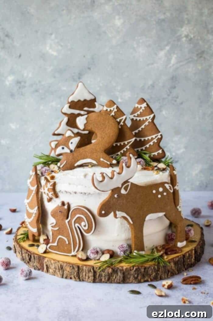 Woodland animal ginger cake on a wooden cake board on a grey background. This impressive vegan ginger cake with lemon curd, cream cheese frosting and whimsical gingerbread woodland animals is a real festive showstopper for Christmas!