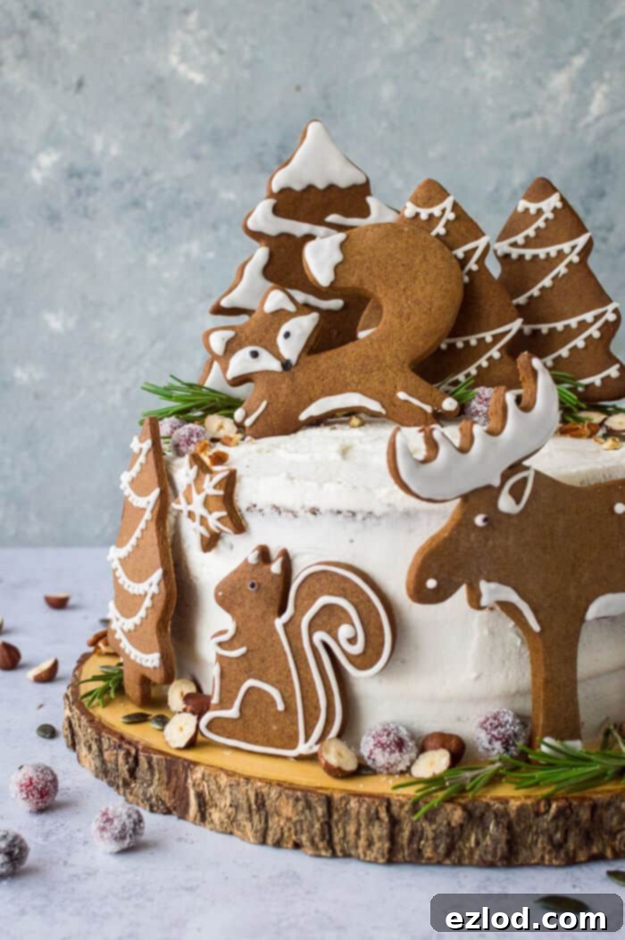 A side shot of a beautifully decorated vegan woodland animal ginger cake, adorned with gingerbread fox, squirrel, moose, and trees, ready for Christmas.