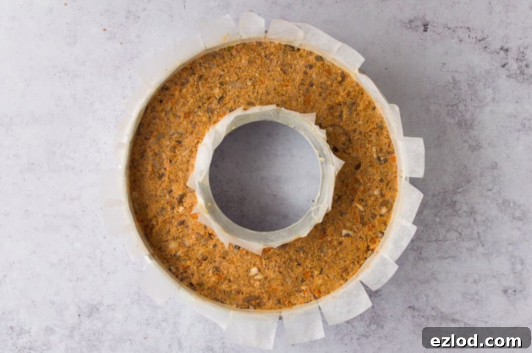 Step-by-step image of the vegan nut roast mixture packed into a lined ring tin, ready for baking in the oven.