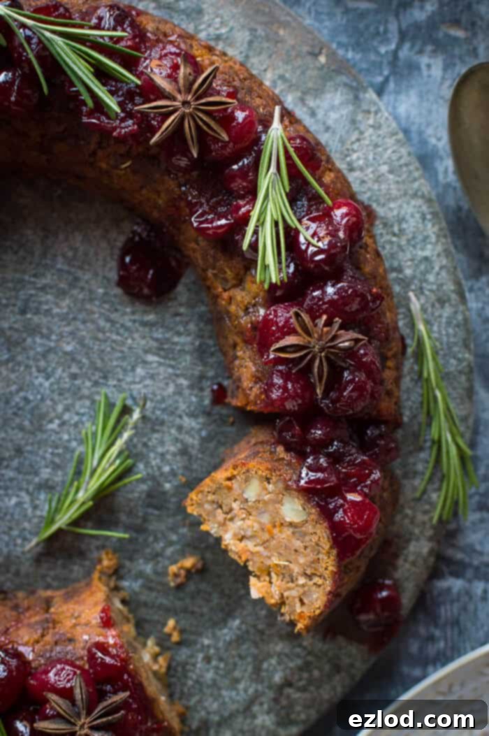 Close-up of a perfectly sliced festive vegan nut roast wreath, revealing its rich texture and wholesome ingredients like mushrooms, chestnuts, and butternut squash, ready to be enjoyed.