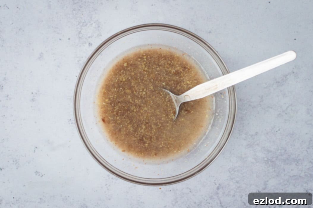 Fudgy Beetroot Chocolate Cake with Avocado Silk Frosting 4 Step-by-step image demonstrating the process of making a flax egg by mixing ground flaxseed and water in a bowl.