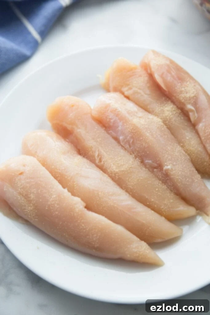 A white round plate of seasoned chicken tenderloins 