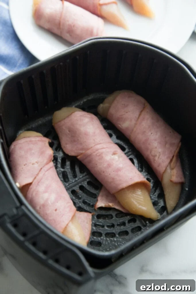 An overhead shot of an air fryer with chicken wrapped in bacon