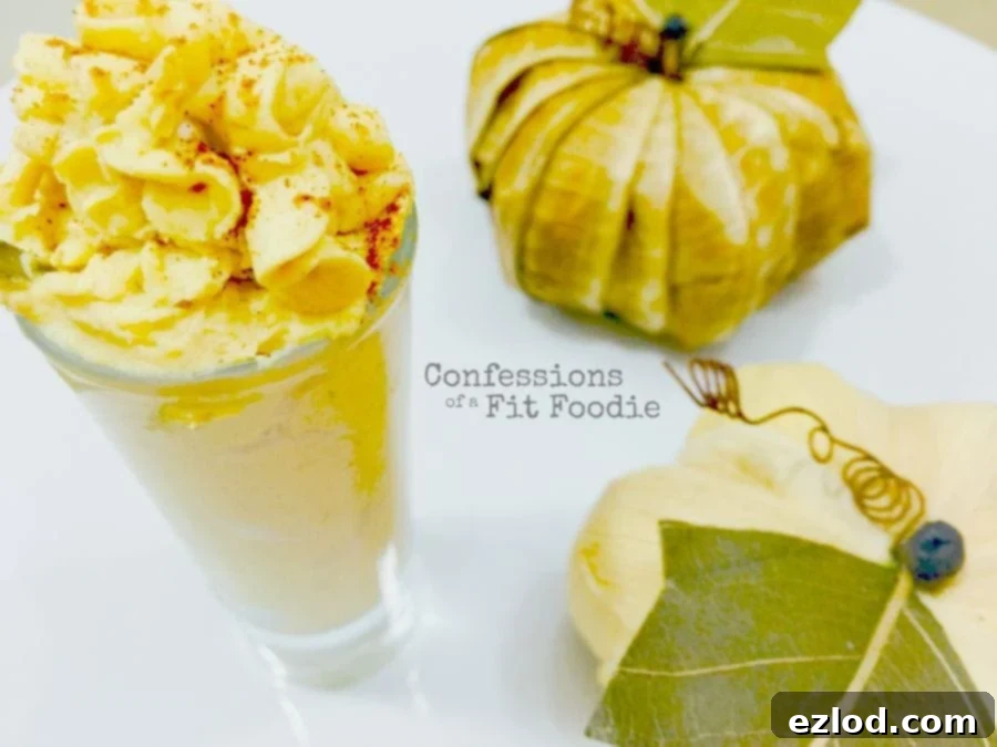 Two pumpkin frosting shooters in small glasses, decorated with fall-themed accessories. This is a healthy 21 Day Fix approved dessert.
