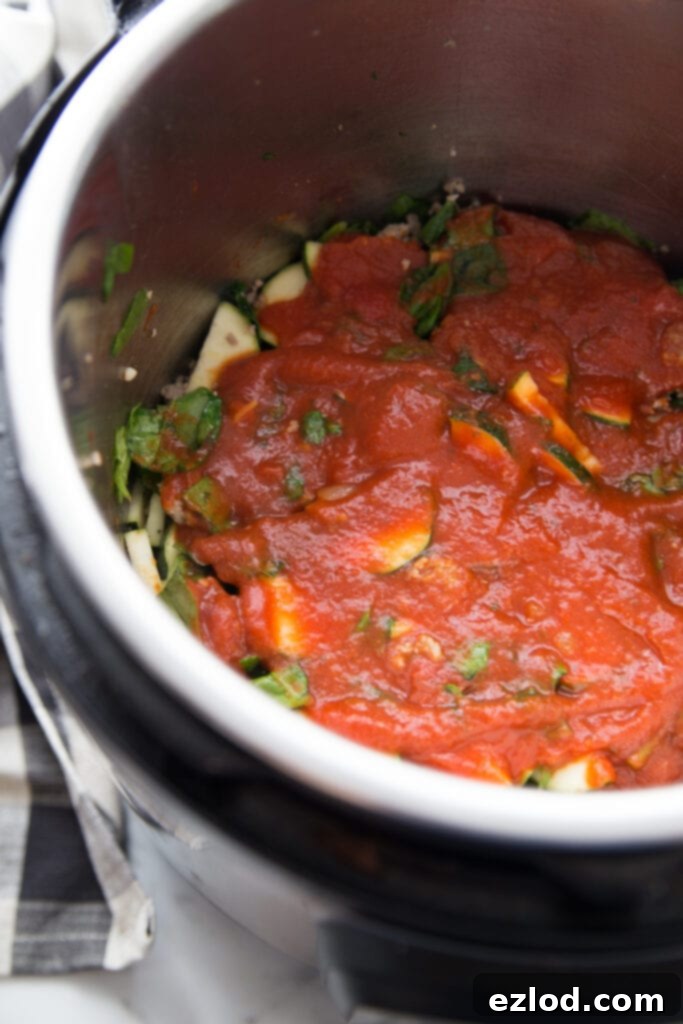A close-up image of the partially cooked Instant Pot Zucchini Lasagna inside the Instant Pot liner, showing the rich meat and zucchini base perfectly cooked before the cheese layers are added. This healthy, easy Instant Pot recipe minimizes cleanup.