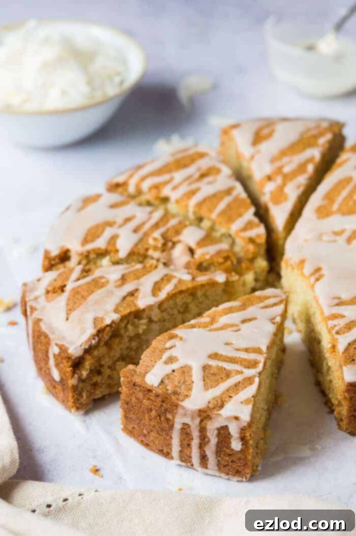A beautifully sliced vegan coconut cake, glistening with lemon glaze, highlighting its moist and tender crumb. Perfect for those seeking an eggless, dairy-free, and truly coconutty treat. #vegan #vegancake #eggless #eggfree #dairyfree #coconut #veganbaking