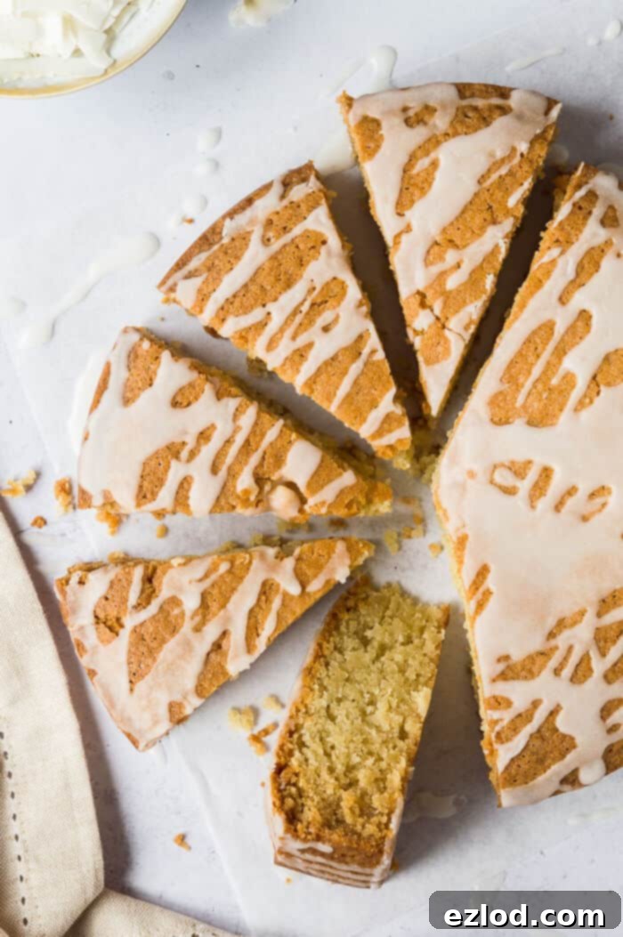 Several slices of moist vegan coconut cake, generously drizzled with a vibrant lemon glaze, arranged on a piece of baking parchment against a stylish grey background. This inviting image highlights the deliciousness of an eggless and dairy-free coconut cake. #coconutslices #vegansnack #plantbasedtreat #easycake