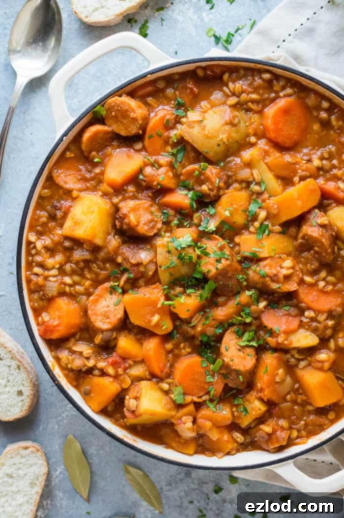 Close up of a white pan full of vegan sausage and lentil casserole topped with parsley.