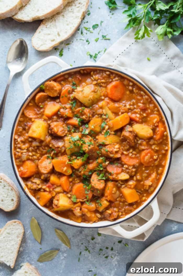 A white pan full of vegan casserole on a grey background with sliced bread, chopped parsley and a cream linen cloth.