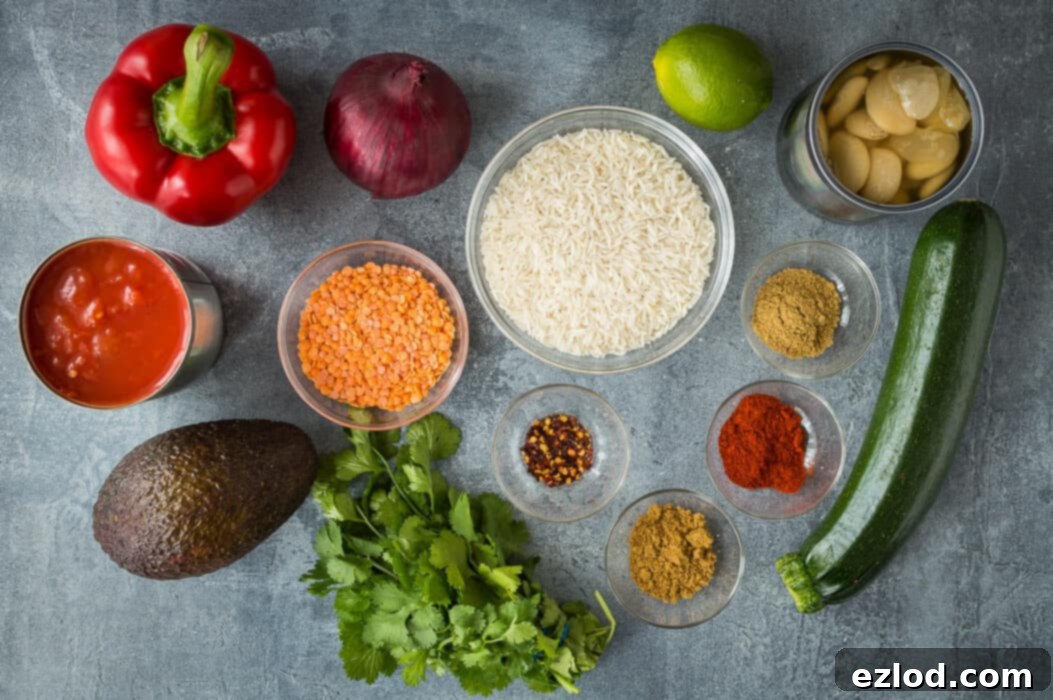 A visual display of all the fresh ingredients required to make the delicious Lentil, Vegetable, and Butter Bean Chilli, including various vegetables, spices, lentils, and canned goods.