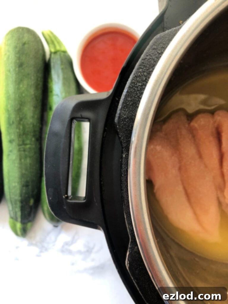 An Instant Pot with Zucchini and hot sauce nearby