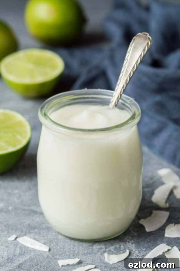 A small glass jar of vegan coconut lime curd with a spoon in it.