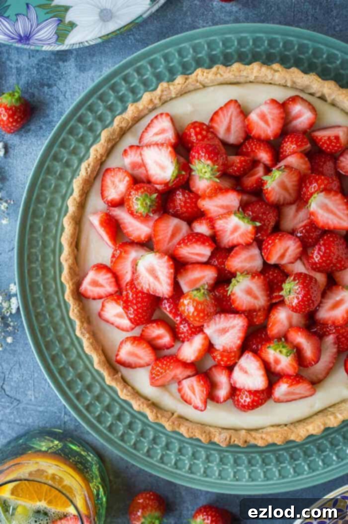 A close-up of a delectable vegan strawberry tart presented on a beautiful green plate, highlighting its fresh fruit topping and creamy filling.
