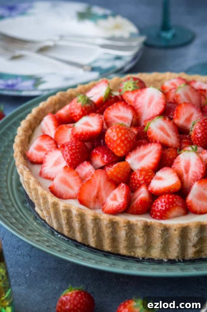 A close-up side view of a vegan strawberry tart, showcasing the delicate, flaky texture of its coconut oil pastry crust.