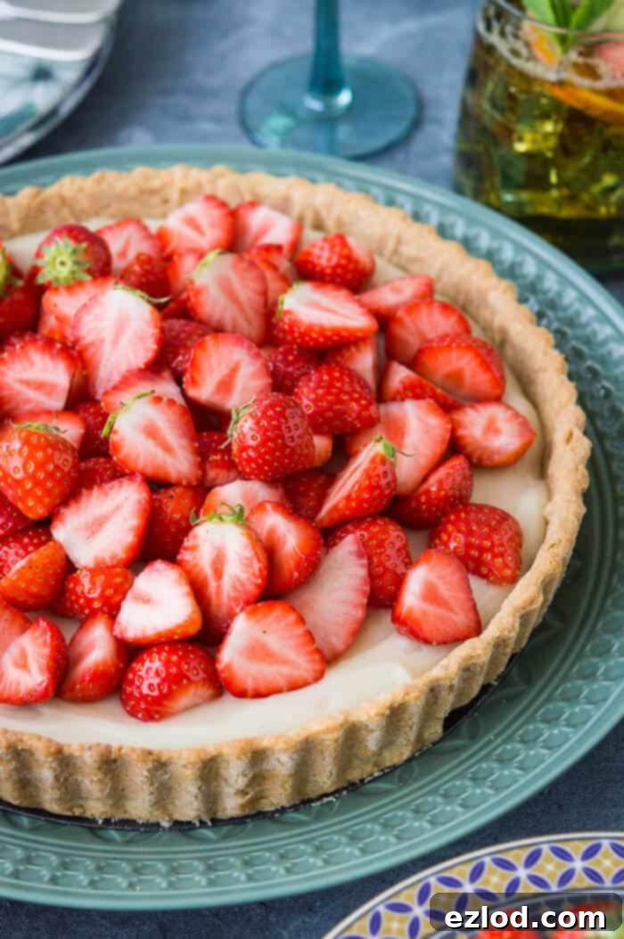 A close-up view of fresh, ripe strawberries artfully piled on top of a creamy vegan tart, highlighting the vibrant colors and delicate textures.