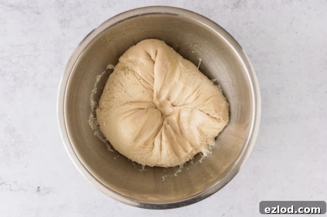 Step 4: A hand gently punching down risen vegan banana bread cinnamon roll dough.