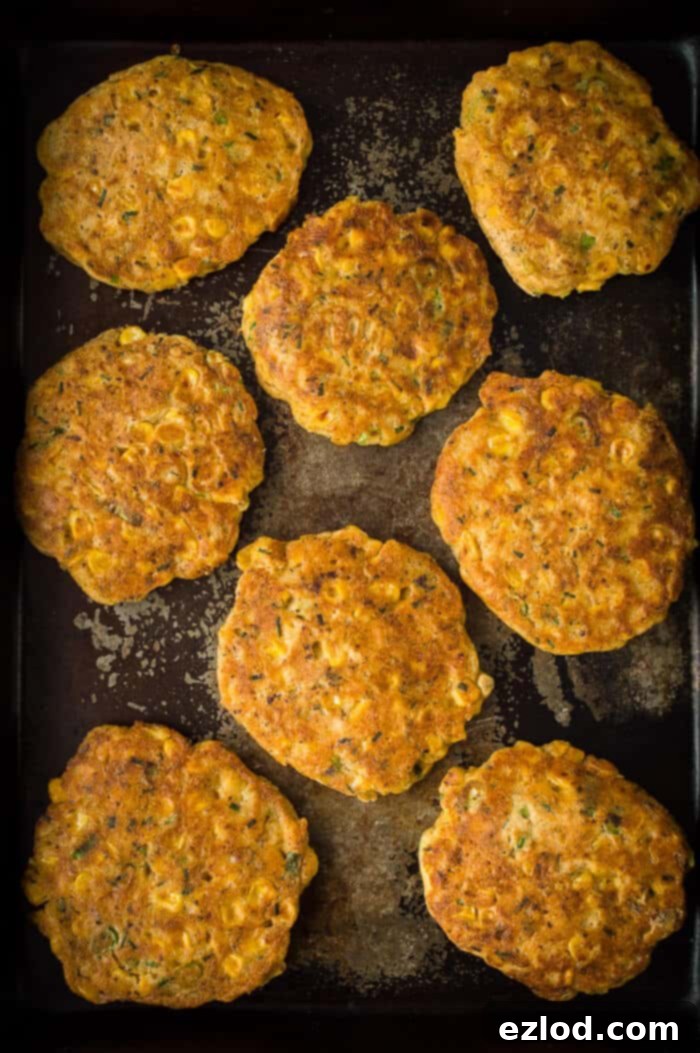Vegan sweetcorn fritters on a dark baking tray.