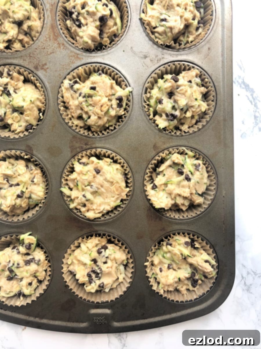 Muffin tin filled with chocolate chip zucchini muffin batter, ready for the oven