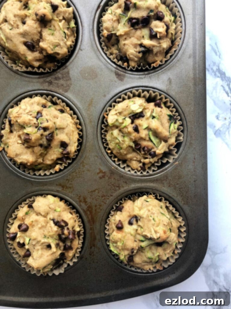 Close up photo of a partial muffin pan filled with fresh out of the oven Gluten Free Chocolate Chip Zucchini Muffins