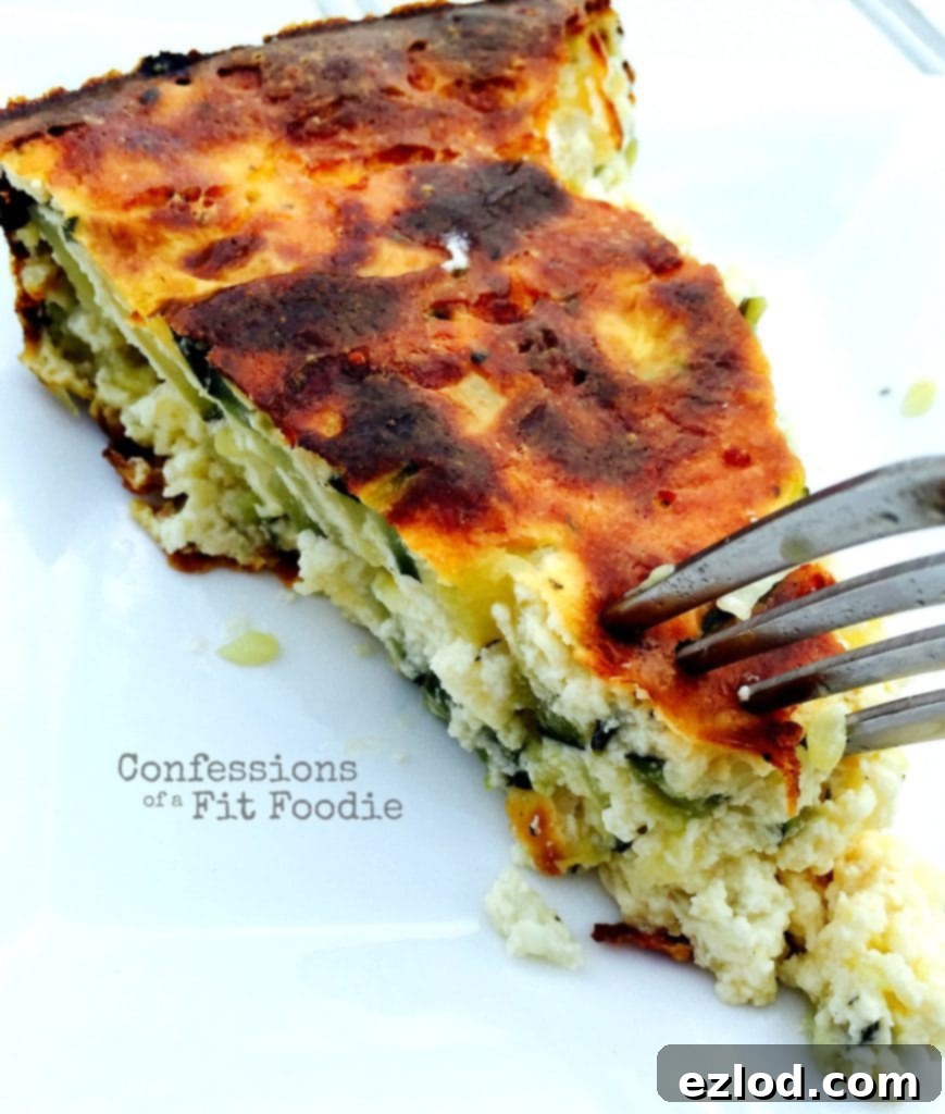 Triangular piece of Crustless Zucchini Quiche being pierced by a fork ready for a bite