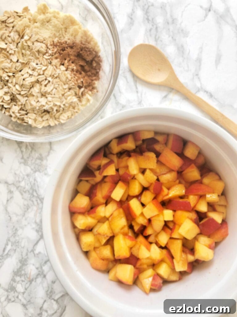 Diced peaches in a large casserole bowl sitting next to a bowl of oats, almond flour and cinnamon - this will be the topping for a Healthy Peach Crisp