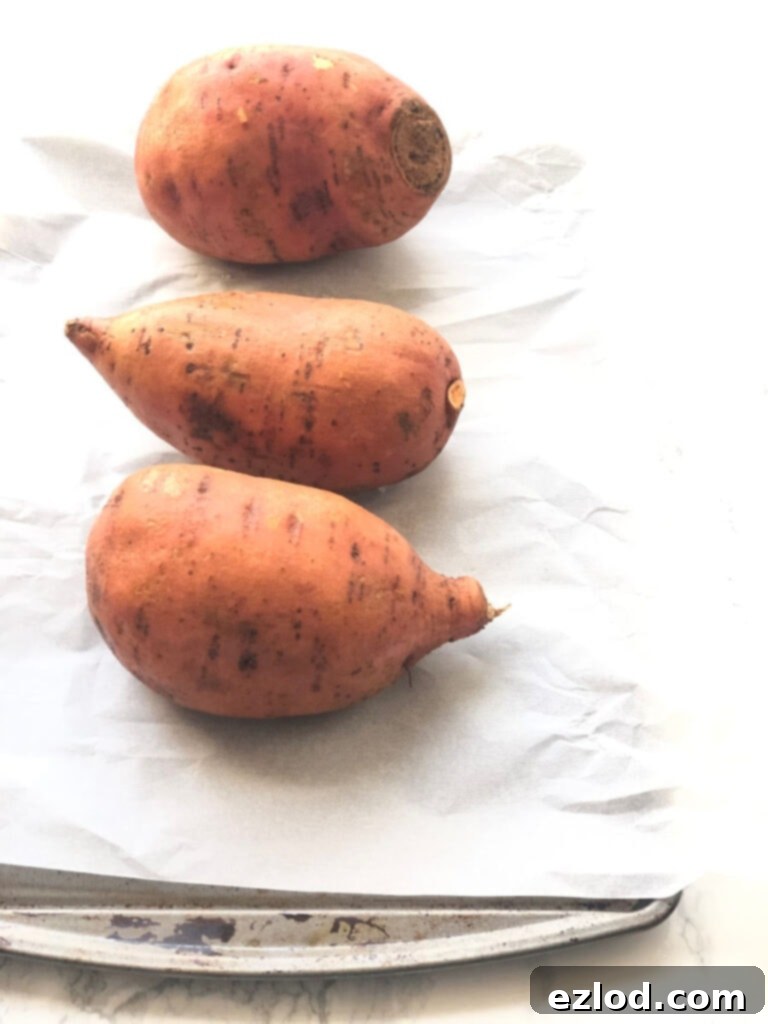 An oven-baked sweet potato, perfectly golden and ready to be stuffed, on a marble countertop