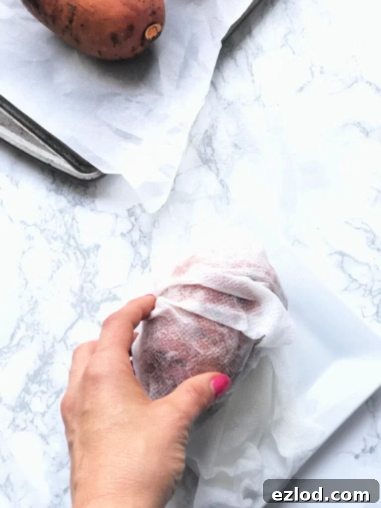 A sweet potato wrapped in a wet paper towel on a marble countertop