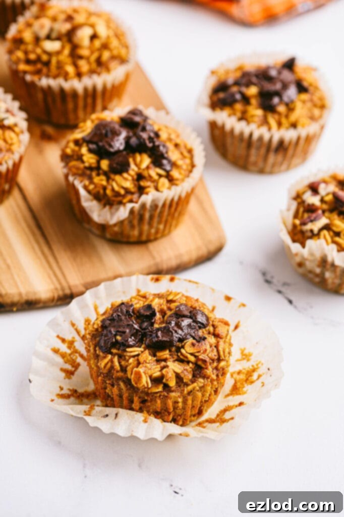 High angle photo of pumpkin oatmeal muffins with various toppings, on a cutting board and white counter.