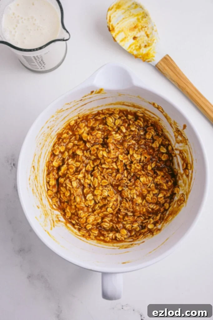 Overhead image: pumpkin oatmeal batter in a white bowl with a spatula off to the side.