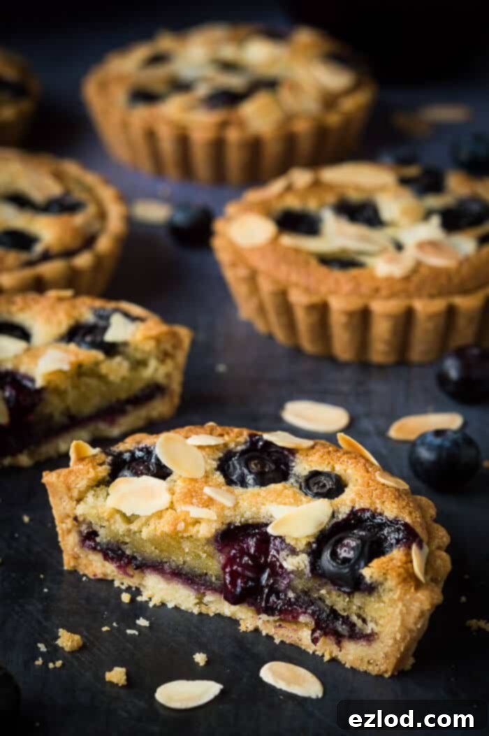 Close up of a blueberry frangipane tart sliced in half.