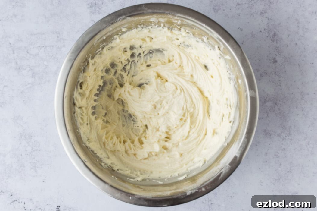 A step-by-step image showing the process of making smooth and fluffy vegan vanilla buttercream in a mixing bowl with an electric whisk, ready to fill the cake.