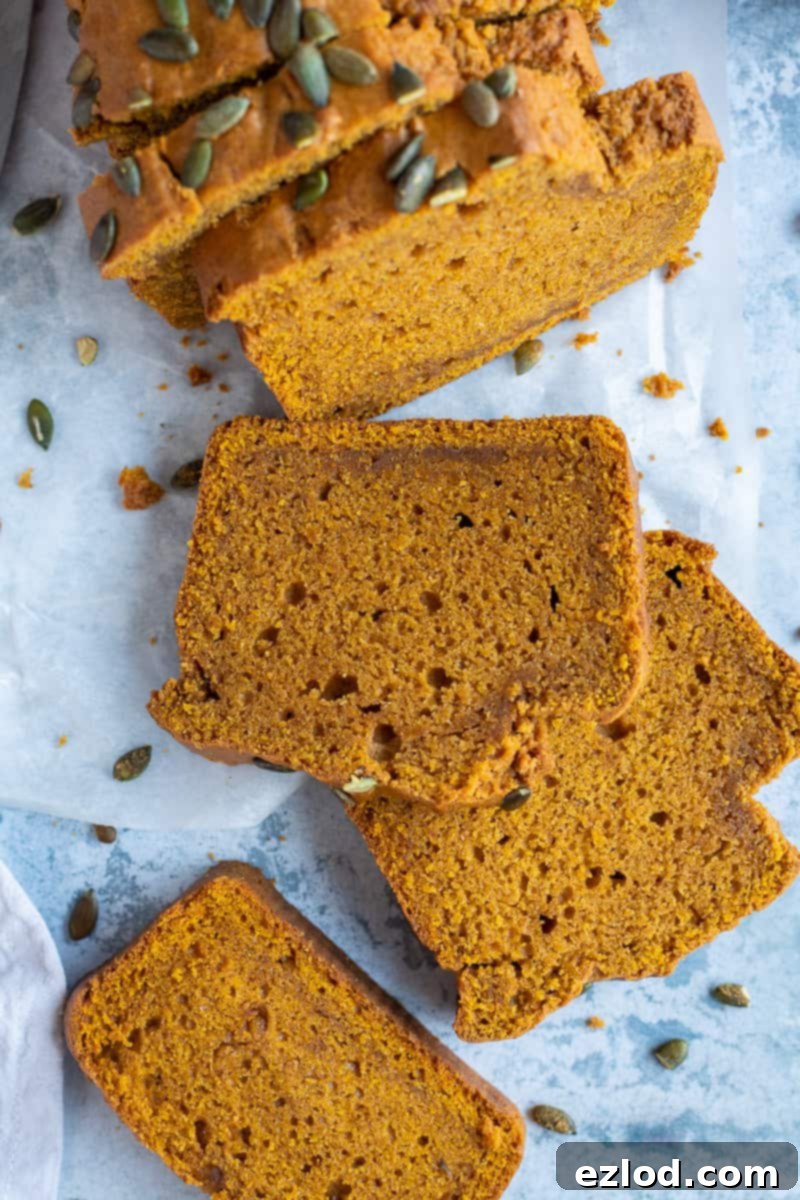 Moist Slices of Spiced Vegan Pumpkin Bread A close-up overhead shot showcasing several perfectly sliced pieces of moist vegan pumpkin cake, arranged invitingly on a blue background.