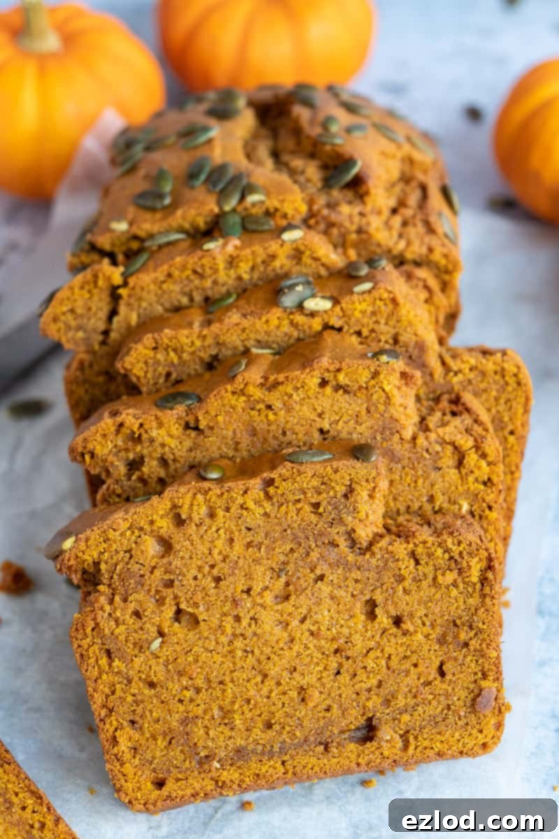 Slices of Homemade Vegan Pumpkin Bread Close-up shot of individual slices of vegan pumpkin loaf cake, with mini pumpkins decoratively placed in the soft-focus background.