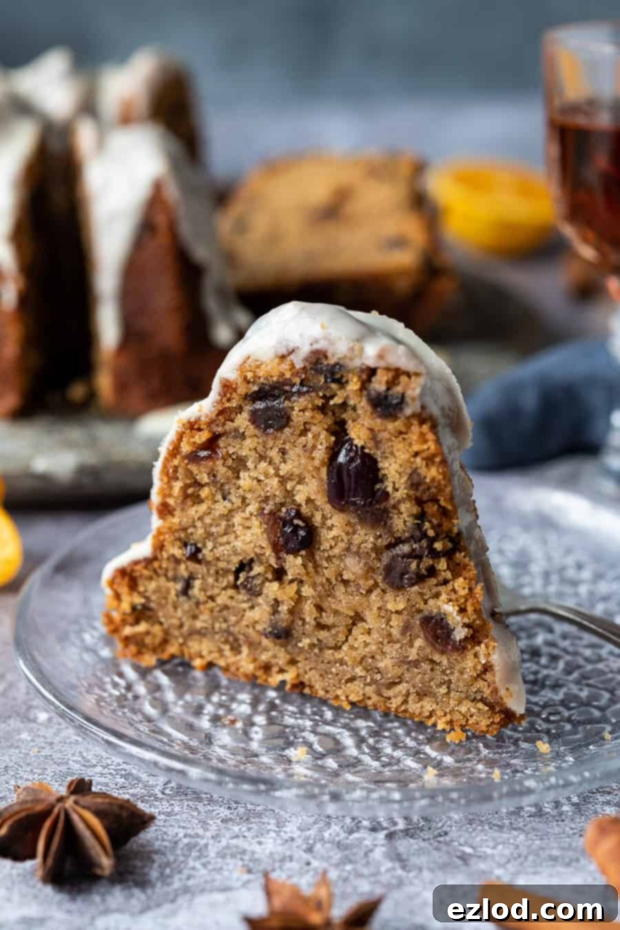 Vegan mincemeat cake - this Christmassy vegan bundt cake is perfect for using up mincemeat (of the fruit variety!) or is a great festive alternative to a traditional Christmas cake. #bundtcake #vegancake #veganbaking #christmascake #christmas #festive #mincemeat A slice of vegan mincemeat cake on a glass plate with the rest of the cake in the background.