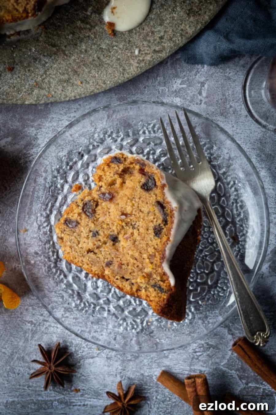 Vegan mincemeat cake - this Christmassy vegan bundt cake is perfect for using up mincemeat (of the fruit variety!) or is a great festive alternative to a traditional Christmas cake. #bundtcake #vegancake #veganbaking #christmascake #christmas #festive #mincemeat A slice of vegan mincemeat cake on a glass plate with a fork.