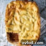 Hearty Vegan Lasagna 9 classic vegan lasagna in a white lasagne dish on a rustic wood surface with a blue and white tea towel, forks, herbs and pewter salt and pepper shakers.
