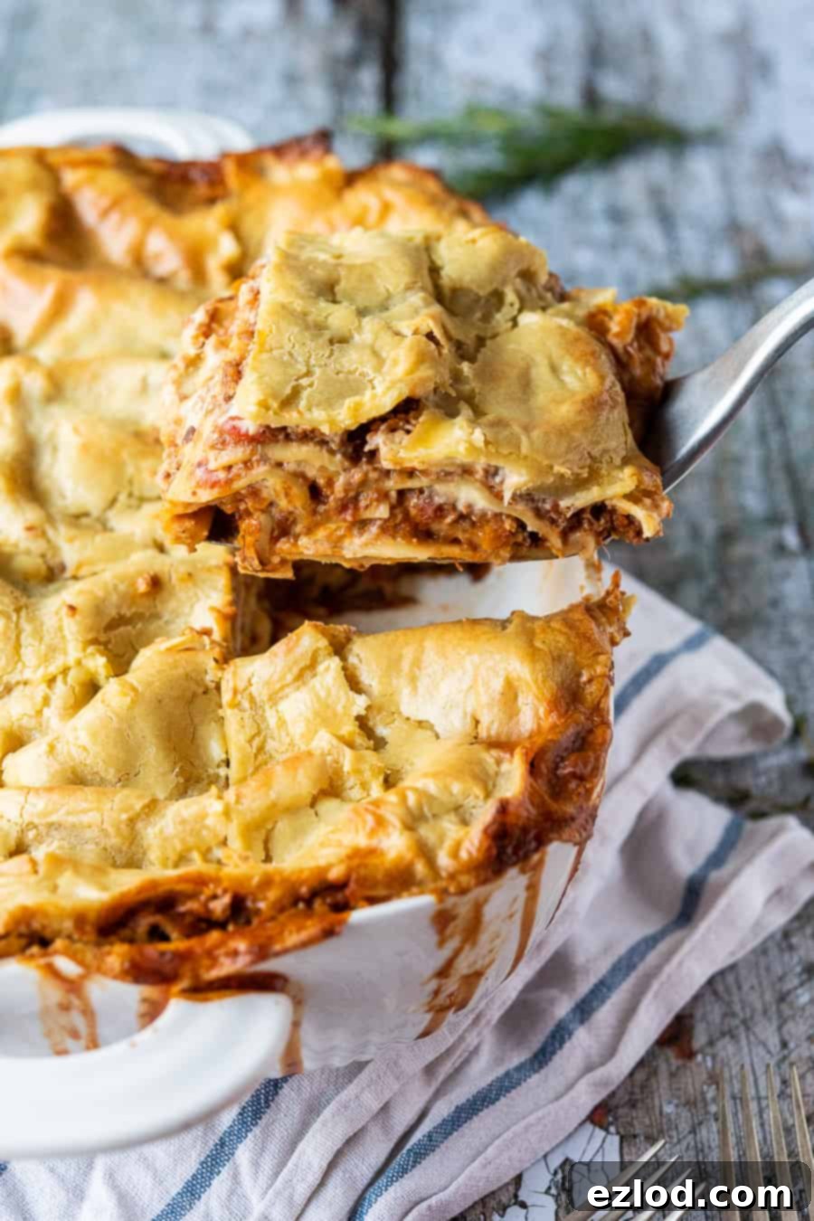 Classic vegan lasagne - this vegan lasagna is seriously good! A rich mushroom ragu is layered up with a creamy dairy-free bechamel sauce and sheets of pasta. It is hearty, filling, totally delicious and healthy too! #lasagna #veganmeals #veganlasagna #plantbased #dairyfree #meatfree A slice of classic vegan lasagne being lifted out of the dish.