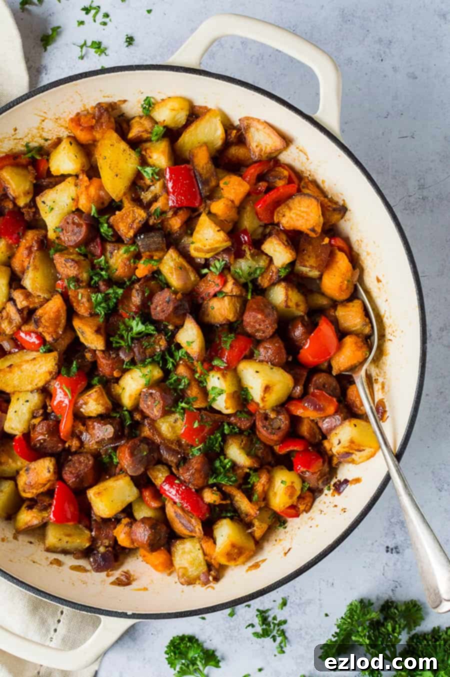 Vegan chorizo and potato hash: A close-up of the smoky, savory plant-based meal. #plantbased #veganhash #chorizohash #easyvegan #brunchideas #dinnerideas Close-up shot of a white cast iron pan filled with perfectly cooked vegan chorizo and potato hash, ready to be served on a grey background.