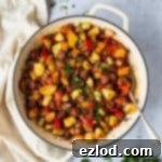 Spicy Vegan Chorizo Potato Skillet 2 a white cast iron pan of vegan chorizo and potato hash on a grey background with fresh parsley and a cream tea towel.