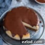 Decadent Vegan Baileys Cheesecake 2 Cheesecake topped with chocolate ganache on a metal plate on a grey background with a bowl of ganache and three forks.