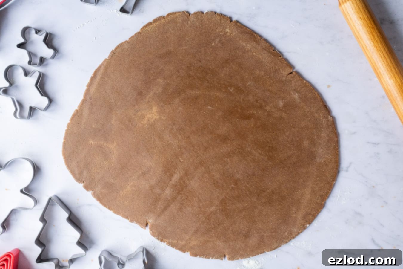 Festive Vegan Gingerbread Cookies 5 Vegan gingerbread dough being rolled out evenly between two sheets of baking parchment.