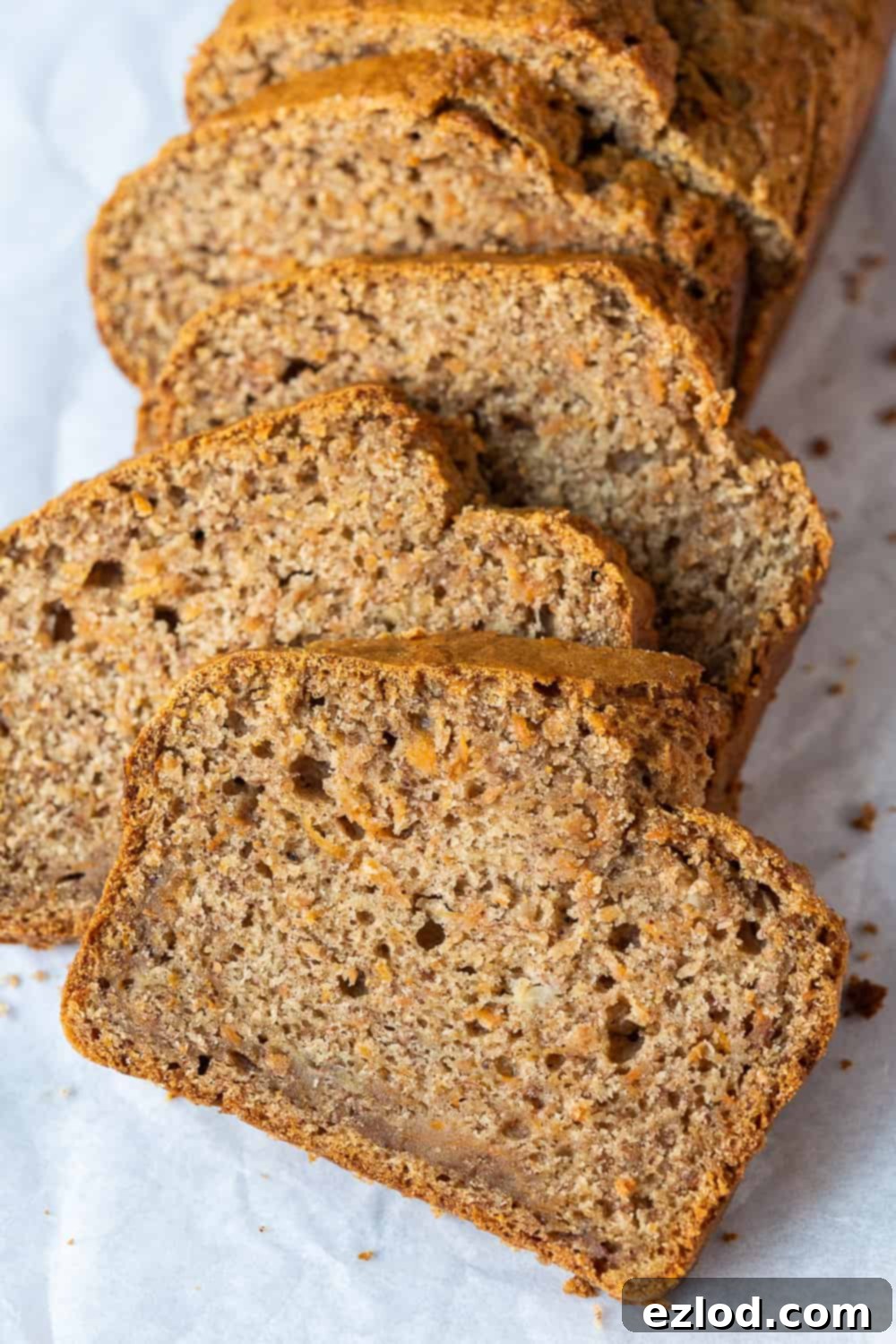Close-up of a Slice of Vegan Carrot Banana Bread - Healthy Plant-Based Snack A close-up view of a single slice of moist vegan carrot banana bread, revealing the tender crumb, specks of grated carrot, and ripe banana texture.