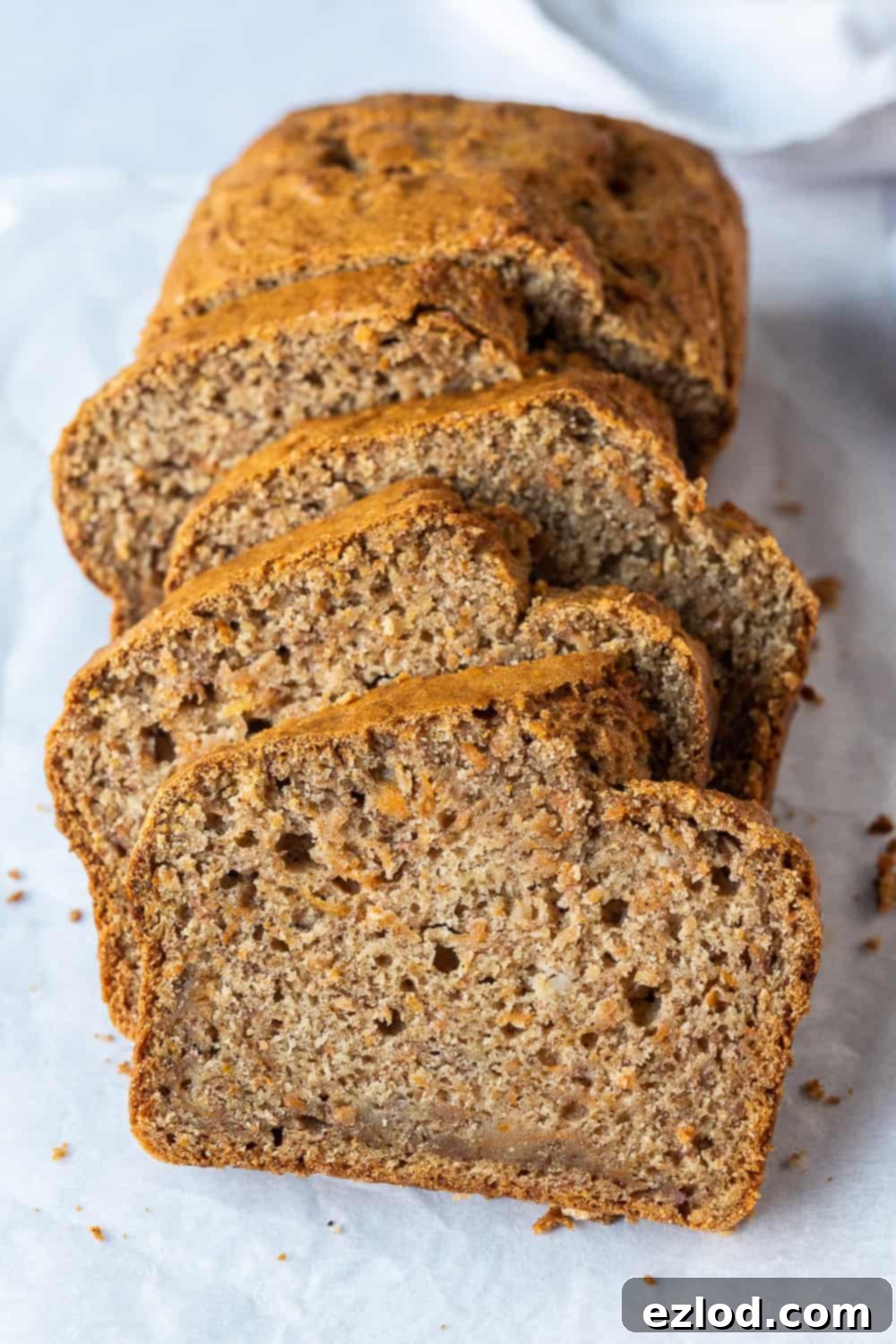 Wholesome Vegan Carrot Banana Bread Loaf - Dairy-Free & Eggless A full loaf of vegan carrot banana bread resting on a rustic grey background, showcasing its perfect bake and inviting texture.