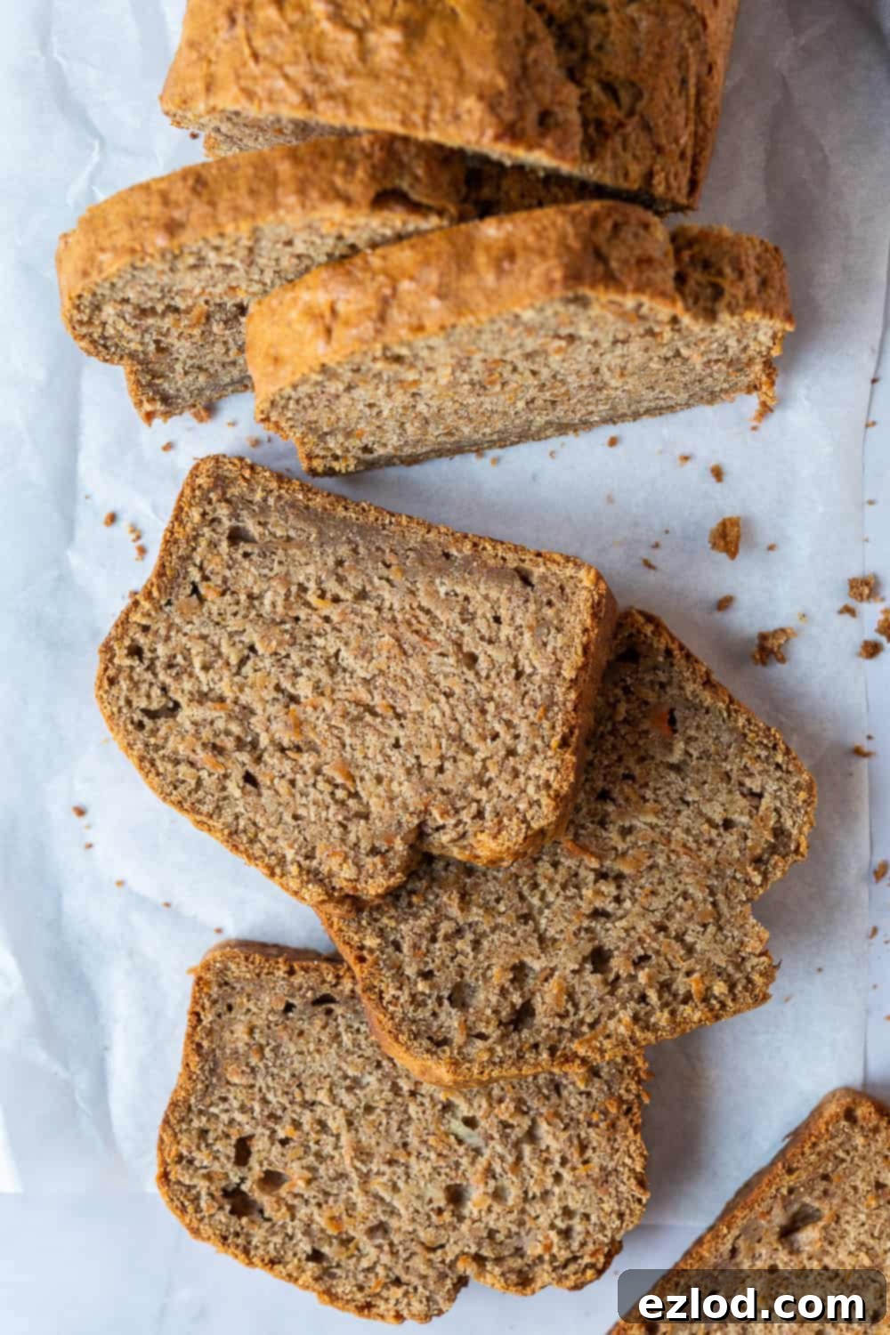 Sliced Vegan Carrot Banana Bread on Baking Parchment A freshly baked and sliced vegan carrot banana bread on a sheet of white baking parchment, highlighting its delicious texture.