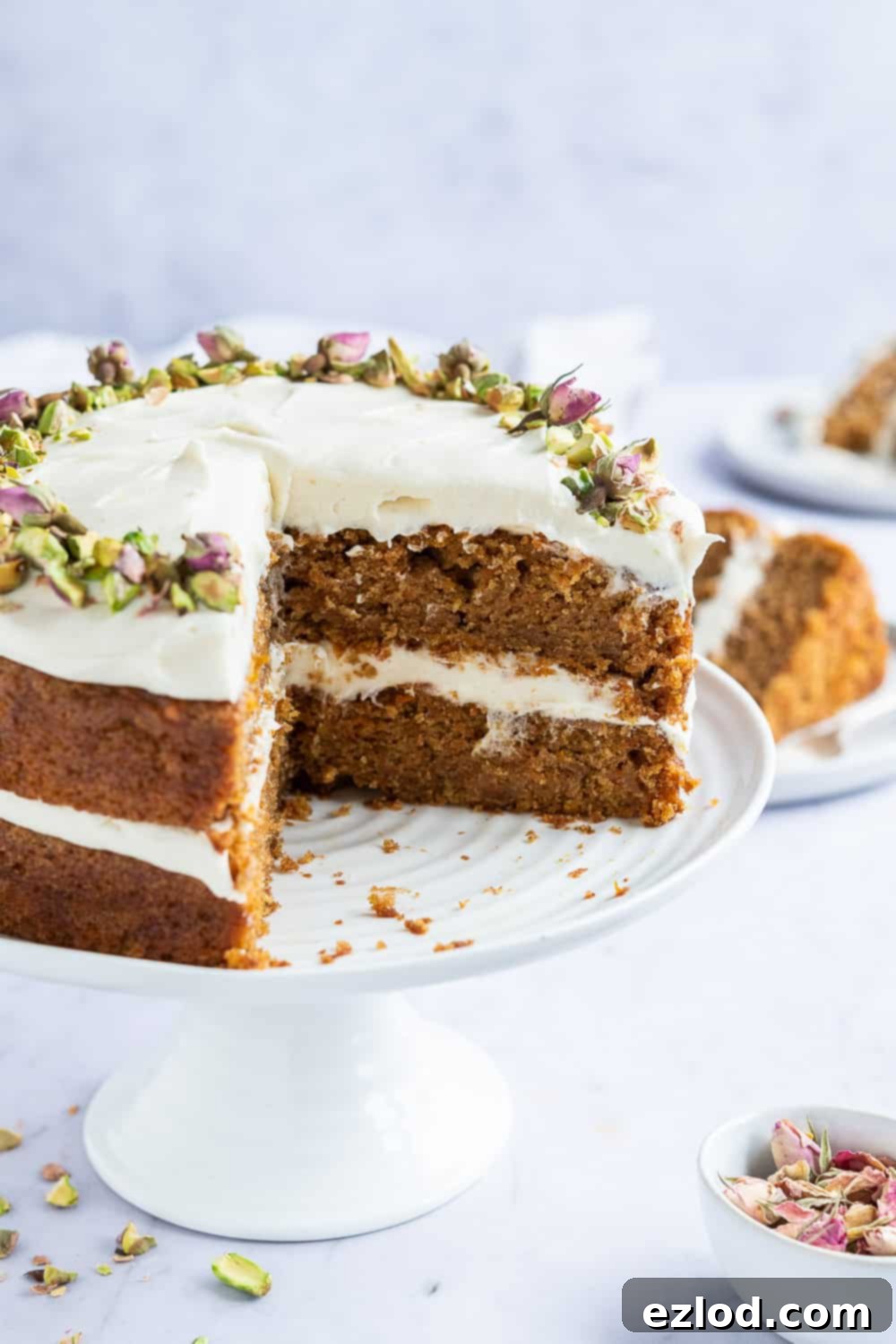 Sliced Vegan Carrot Cake A neatly sliced vegan carrot cake presented on a pristine white cake stand, highlighting its layers.