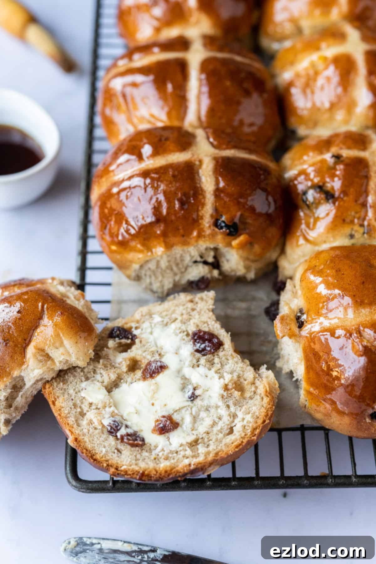 Toasted Vegan Hot Cross Bun with Vegan Butter - A Delicious Easter Snack. #veganbaking #easter #easterrecipes #veganbread #veganrolls A vegan hot cross bun sliced in half and generously spread with vegan butter, showcasing its soft, moist texture. A tempting image for a dairy-free and eggless Easter treat.