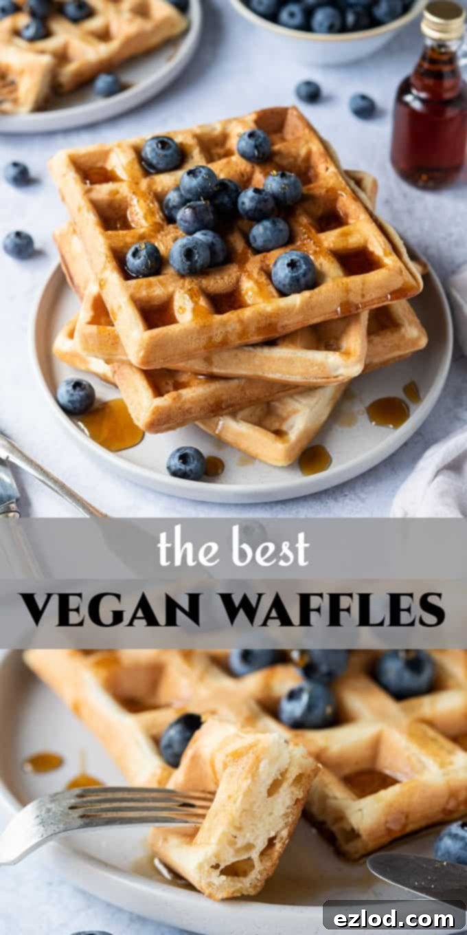 Vegan waffles - these amazing vegan waffles are crispy on the outside and soft and fluffy on the inside; the ultimate vegan breakast! Eggless and dairy free and no banana! Includes options for making them with or without aquafaba. #veganbreakfast #veganwaffles #brunch #breakfast A Pinterest-optimized image featuring a stack of vegan waffles on a grey plate, adorned with blueberries and maple syrup, designed to attract viewers interested in vegan breakfast, waffle, and brunch recipes.