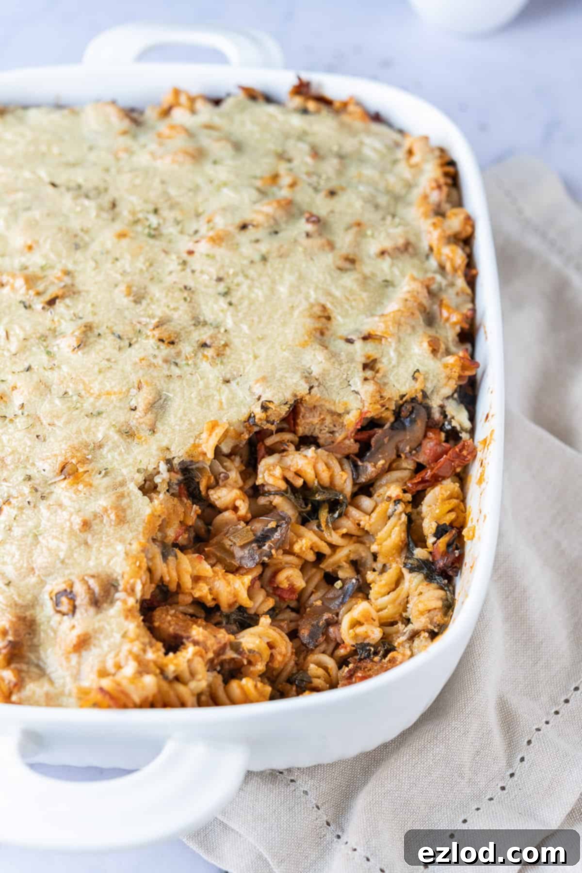 Delicious Dairy-Free Pasta Bake Dairy-free pasta bake in a white lasagne dish, presented on a cream fabric.